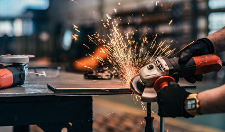 Grinding metal part at factory workshop, close-up.